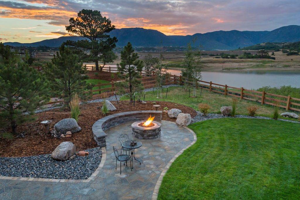 Scenic picture of Colorado sunset with fire pit on stamped concrete and benches close by.